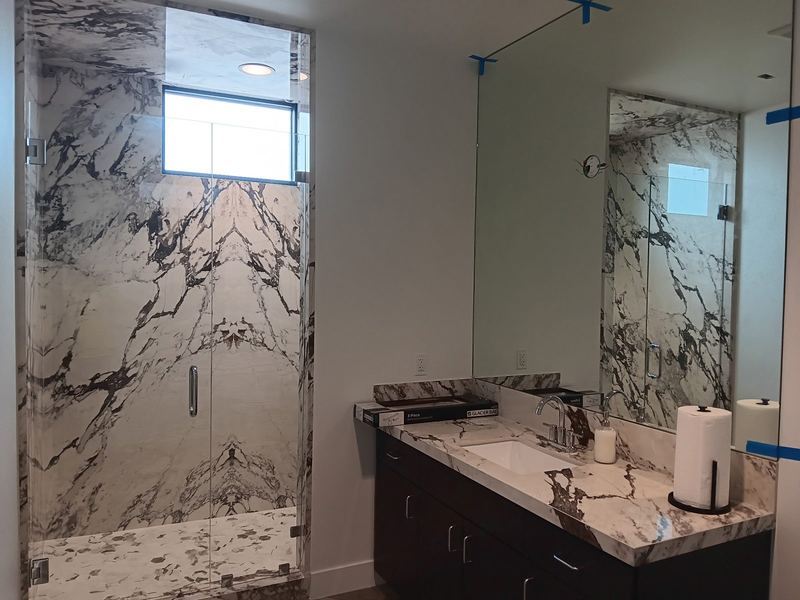 A large wall mirror installed above a double vanity in a marble bathroom