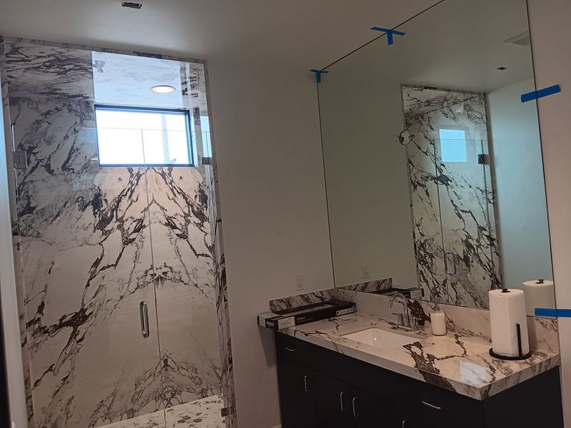 A marble bathroom with a full width vanity mirror above a double vanity