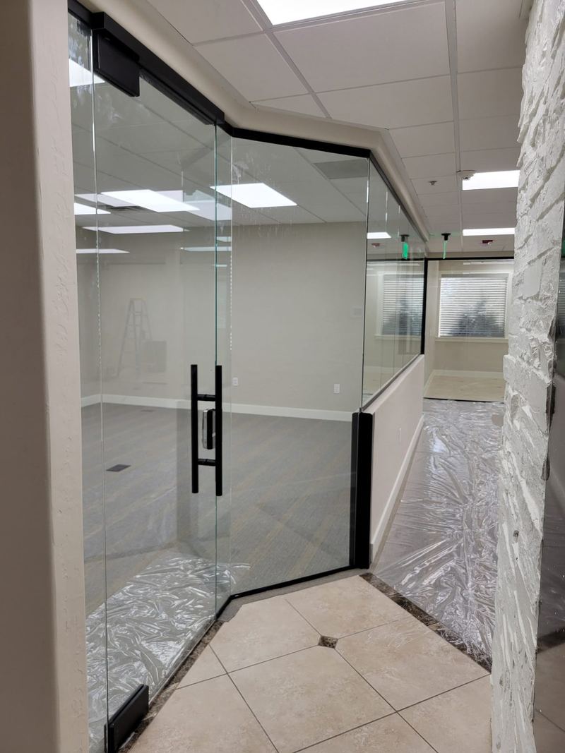 A frameless glass door and partition panel fitted against a stone feature wall