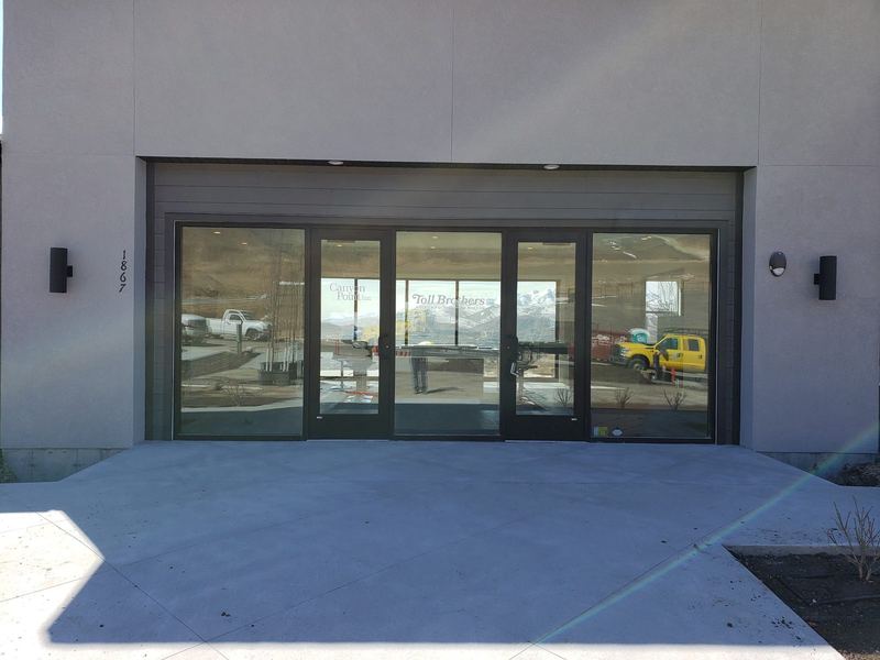 A finished commercial storefront entrance with dark framing and full height glazing