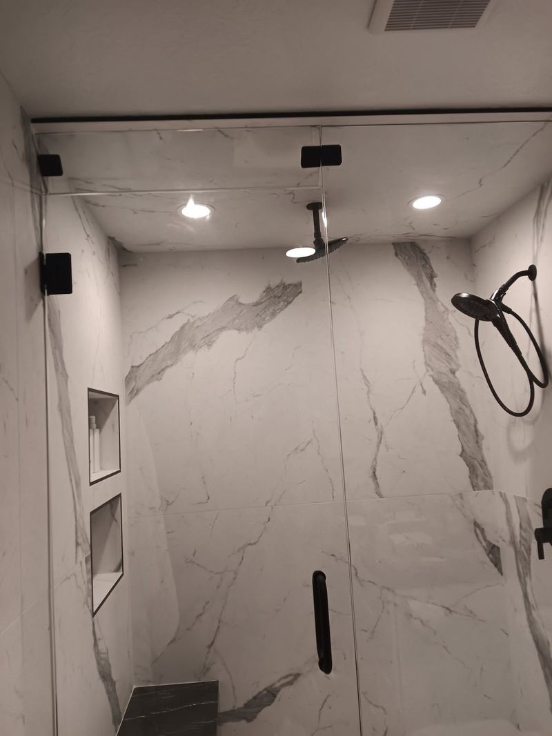 Inside a frameless marble shower enclosure with recessed shelving