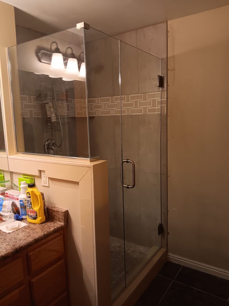 A frameless shower enclosure fitted in a neutral tiled bathroom