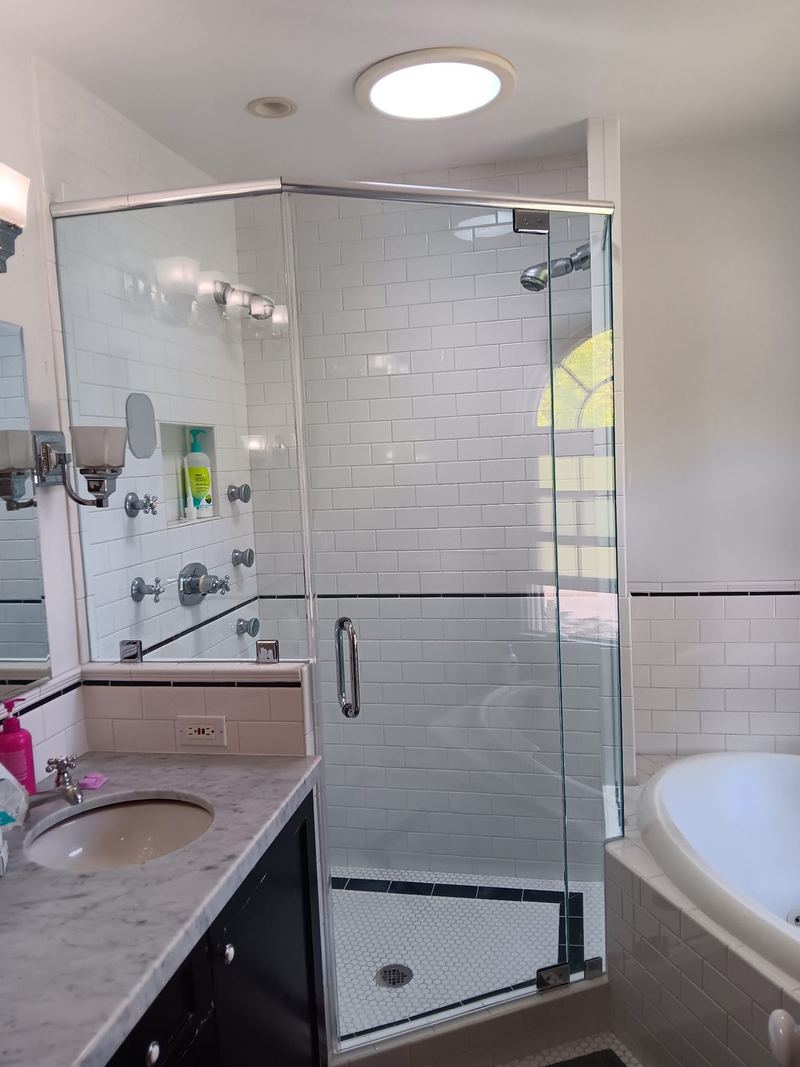 A semi frameless shower enclosure fitted against subway tile beside a bath